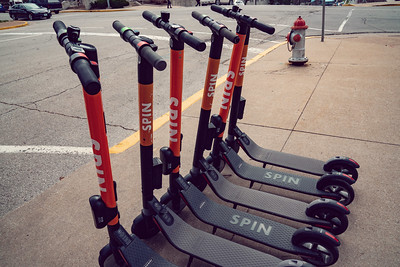 Several Spin scooters on a sidewalk.